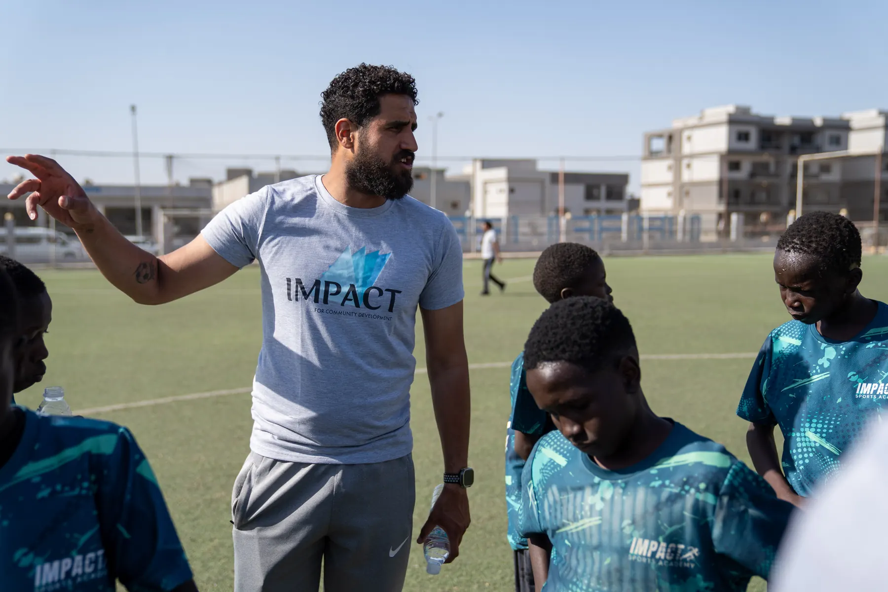 A coach talks with academy players on the pitch