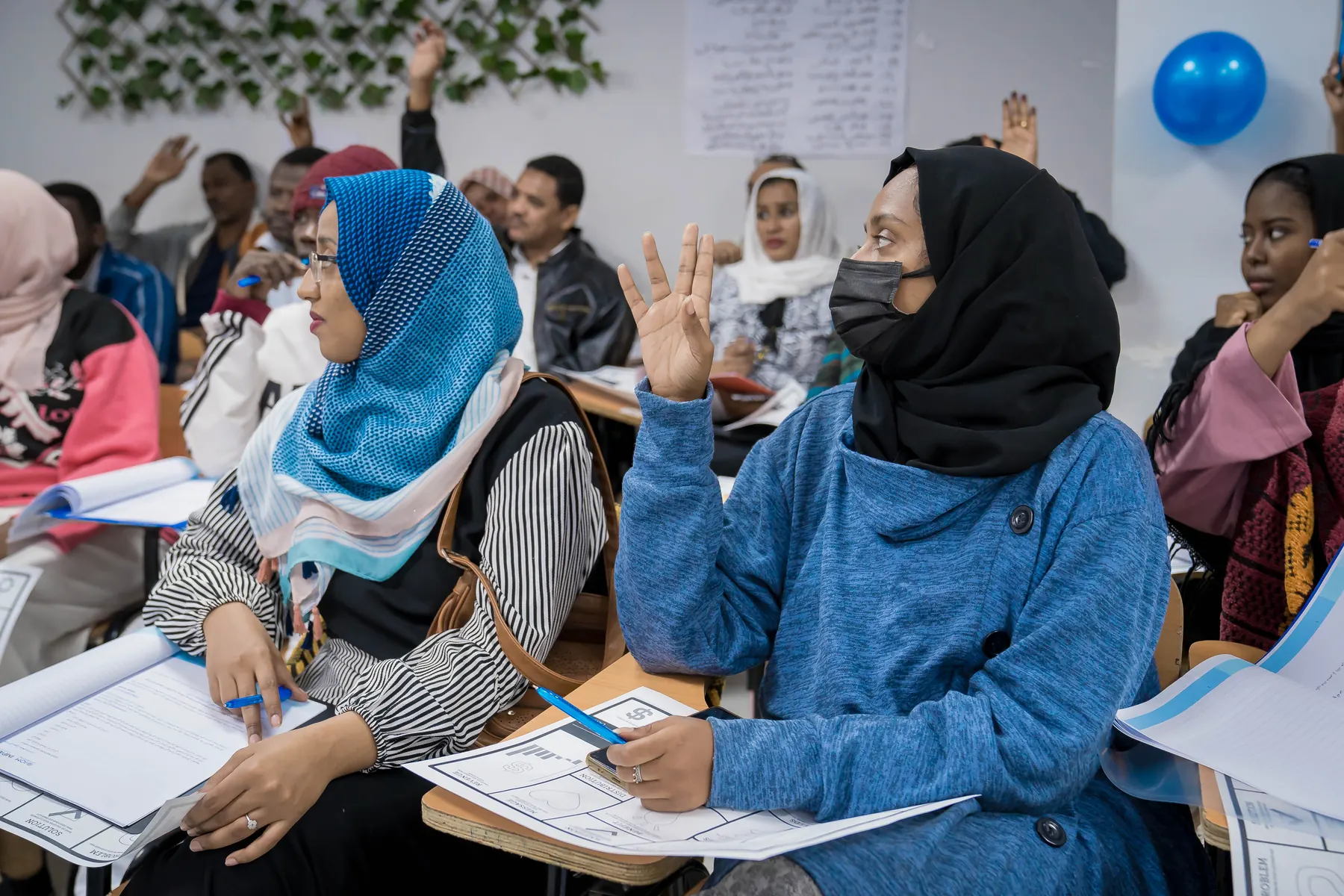 Participants raise their hands during a classroom session