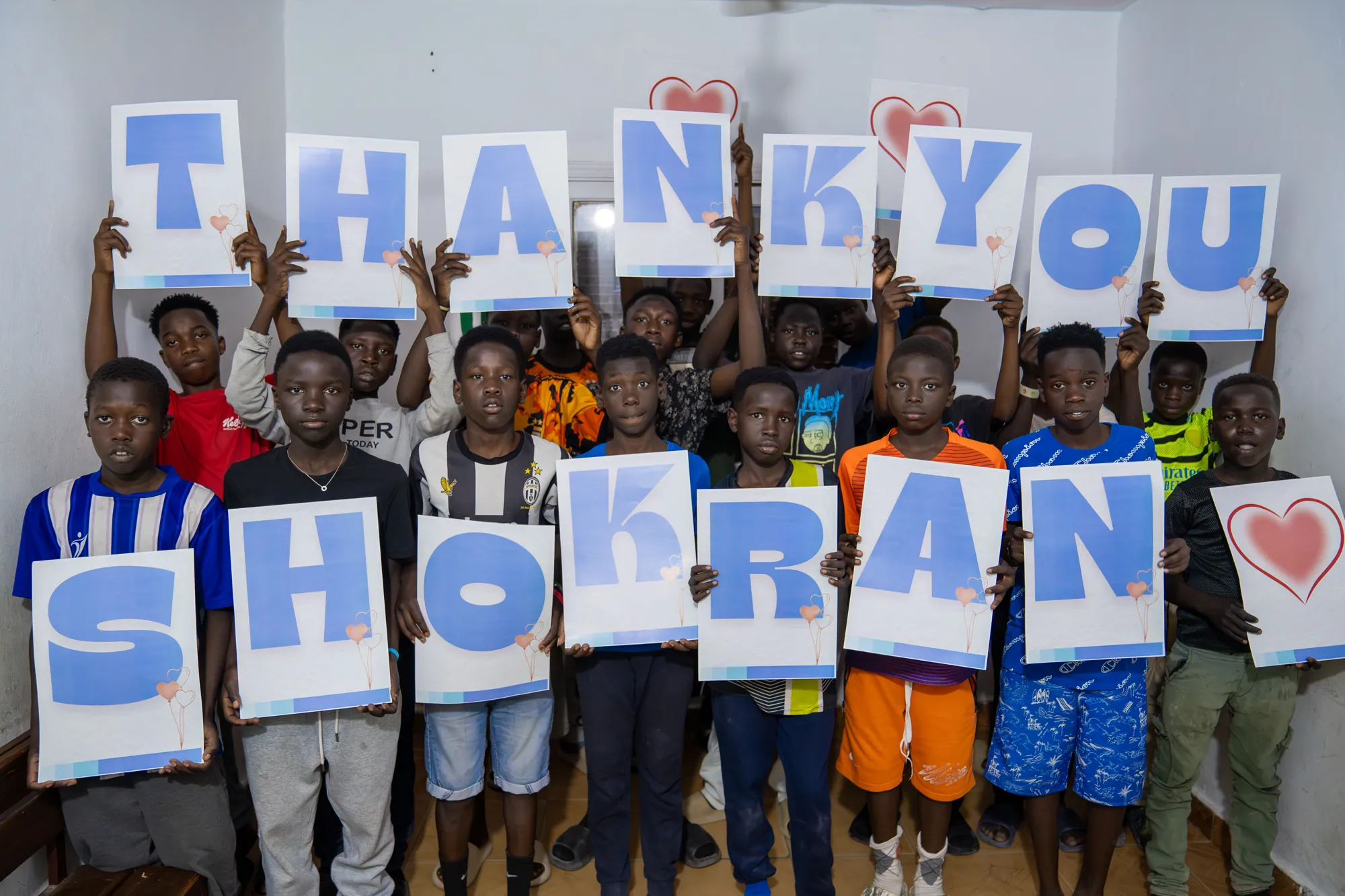 Children from our programs holding up “Thank you – Shokran”