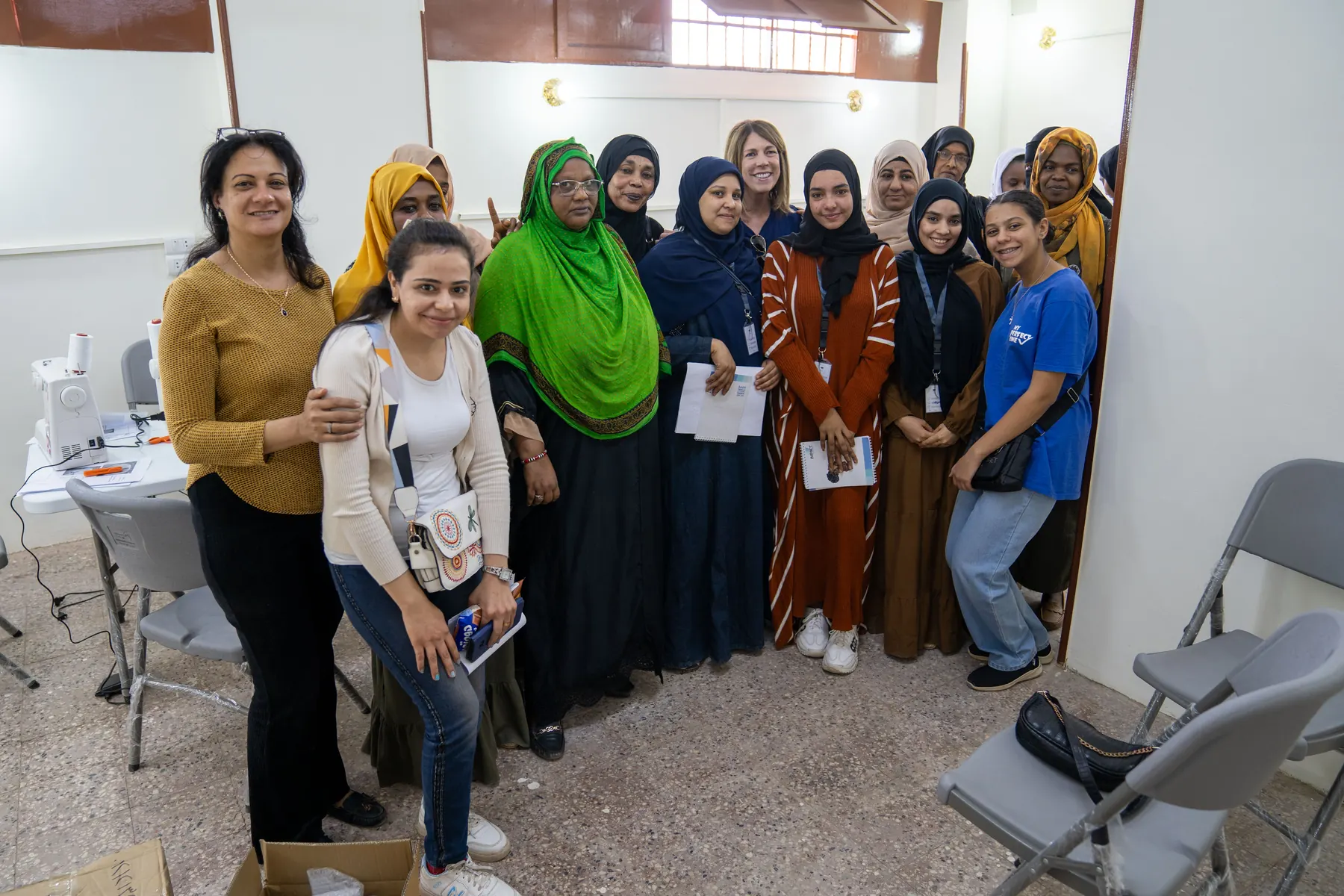 Trainees and trainers gather around a sewing machine in Aswan