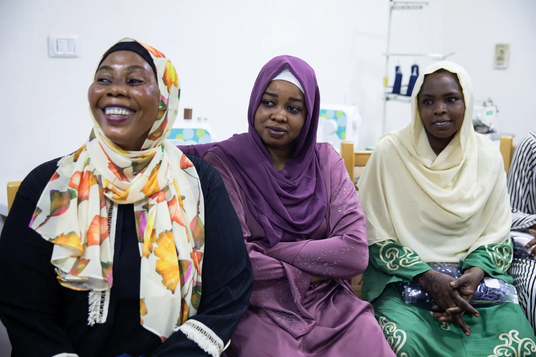 Three women smile together during a training session